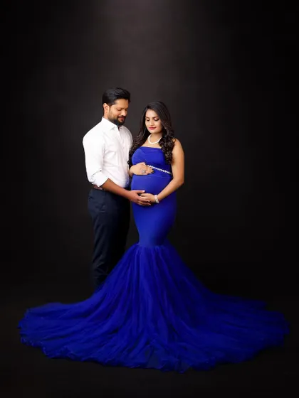 A classic couple's portrait against a dark backdrop. The vibrant blue of her gown provides a beautiful pop of color, creating a simple yet striking image.