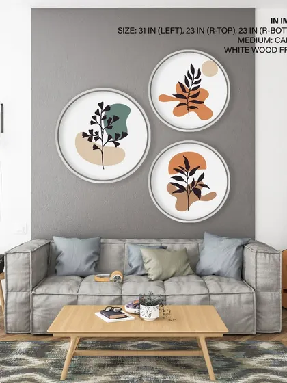 This set of three circular prints features bohemian minimal leaf designs. The simple silhouettes and earthy color palette, framed in clean white wood, create a modern and calming effect.