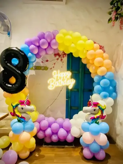 A magical unicorn-themed birthday party with a rainbow balloon arch. This setup includes unicorn-shaped balloon pillars and a neon sign, perfect for an 8th birthday celebration.