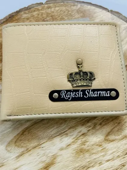 A cream-colored croc-textured wallet with a black name strip and a crown charm, offering a classic and clean look.
