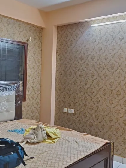 A gold damask wallpaper installed as a feature wall behind a bed.