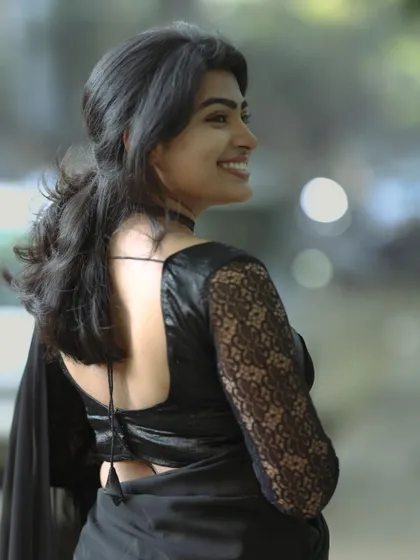 This shot highlights the back of the blouse and a side profile. The makeup remains flawless, with a soft contour and a natural smile, perfect for fashion or portrait photography.