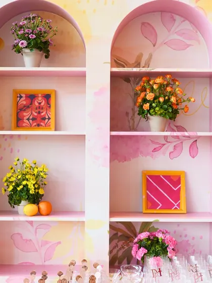 Details from the vibrant Haldi decor, featuring colorful framed art and potted flowers on custom-built shelves.