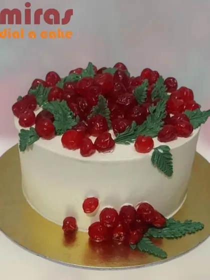 A beautiful cake topped with glistening red cherries. The simple white frosting provides a perfect backdrop for the vibrant fruit, creating a classic and appealing look.