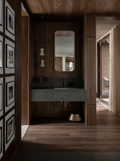 Another view of the wood-paneled powder room, showing the gallery wall of family photos. This personal touch makes the space feel warm and integrated with the rest of the home.