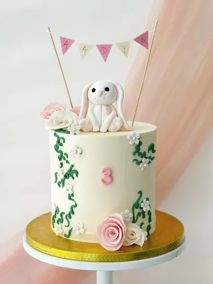 A lovely bunny-themed cake for Adya's third birthday. This design features a fondant bunny, climbing ivy, and delicate pink and white sugar flowers.