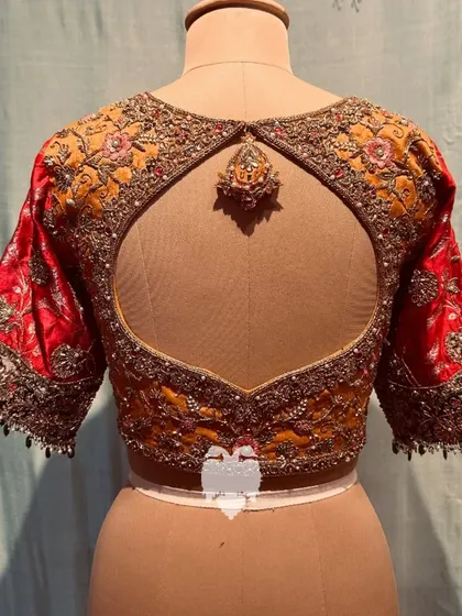 The back of the two-toned blouse, featuring a stunning keyhole cutout and an embroidered tassel.