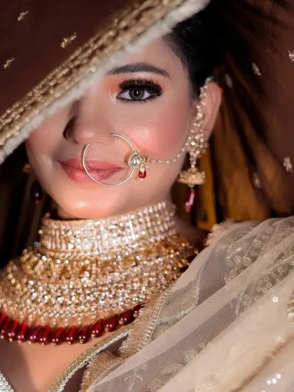 A captivating close-up of a bride peeking from behind her dupatta. This shot creates a sense of mystery and highlights her beautiful eyes and nose ring.