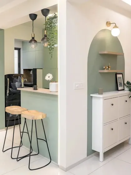 A stylish breakfast bar in sage green, with an arched niche for a shoe rack nearby. The design is both beautiful and practical.