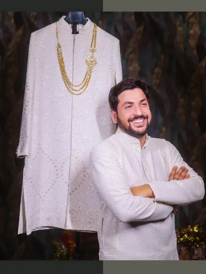 The groom poses next to his wedding sherwani. This creative shot captures his anticipation and excitement before the main event.