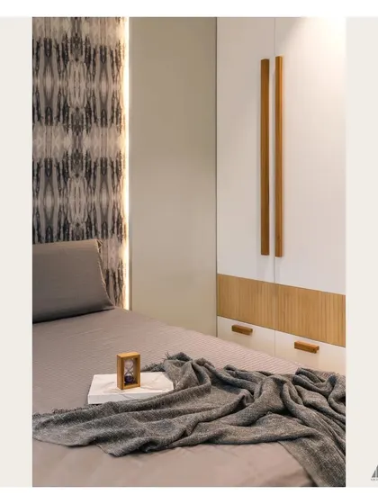 Detail of the two-tone wardrobe with long wooden handles. This element ties in with the patterned headboard wall and adds warmth to the room's contemporary grey theme.