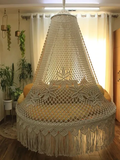 A full view of our bed swing in a natural off-white color. The canopy is covered in a beautiful floral macrame pattern, making it a true statement piece.