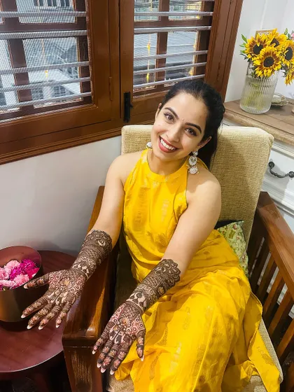 A radiant bride in a bright yellow outfit, her smile as stunning as her intricate henna.