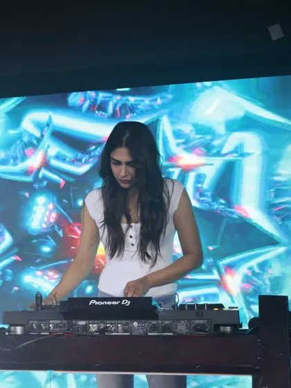 A clear shot of me at the Pioneer DJ console at Ibiza, Jhansi, with a stunning blue visual display in the background. This highlights the quality of the gear and production at my shows.