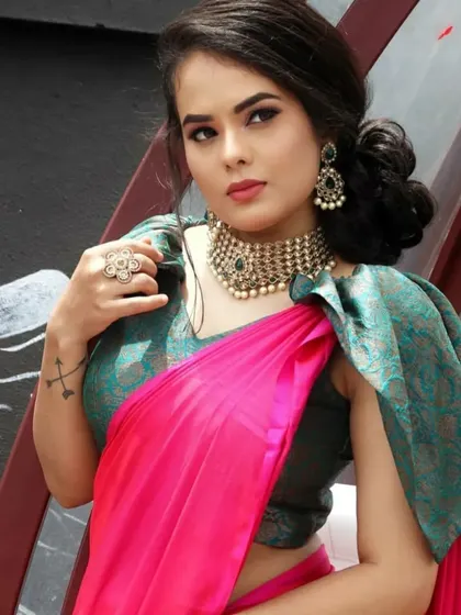 A model in a modern pink saree with a stylish puff-sleeve blouse, paired with an antique-finish choker.