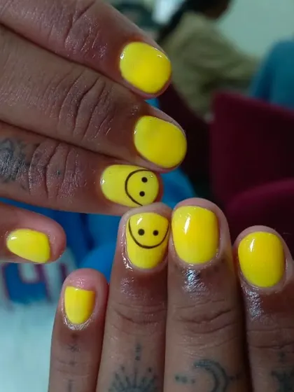 A fun and bright solid yellow manicure with a cute smiley face accent nail for a touch of personality.