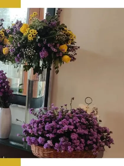 A close-up of the purple and yellow floral arrangements, with a basket of purple asters in the foreground, showcasing the rich color combination.