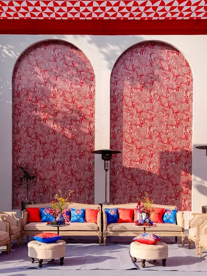 The lounge area combined bold red patterned walls with neutral sofas and vibrant blue and red cushions for a striking look.