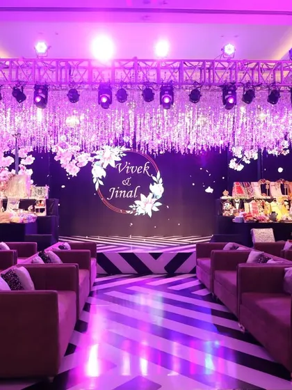 A dramatic Sangeet stage setup with a ceiling of shimmering crystals and bold purple lighting. The striped black and white floor adds a modern, graphic element to the glamorous design.