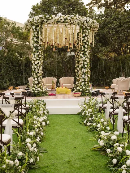 An elegant outdoor mandap, framed by pillars of white roses and lush greenery. We work with you to design a sacred space that feels both traditional and contemporary, ensuring the setting for your vows is as beautiful as the commitment you are making.