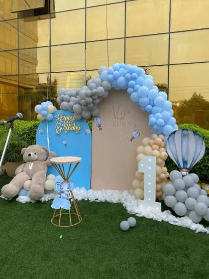 The complete outdoor setup for Ved's first birthday, showcasing the balloon arch, themed backdrops, teddy bear, and hot air balloon sculpture.