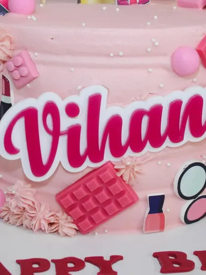A close-up of the personalized "Vihana" name plaque on the pink themed cake.