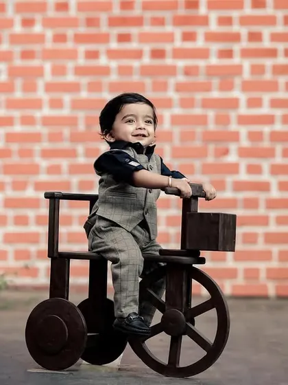 A dapper little gentleman on his wooden tractor. The brick wall and green plants in our studio garden offer a variety of textures and backgrounds.