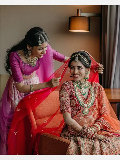 A sweet moment between the bride, Maheswari, and her bridesmaid, who helps her with her veil.