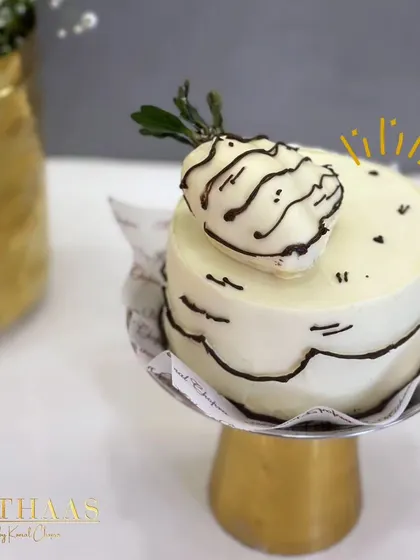 A playful take on a Ferrero Rocher cake. This mini cake features a cartoonish black and white design, topped with a white chocolate-dipped strawberry for a whimsical touch.