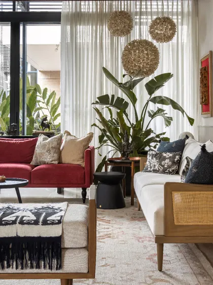 The combination of the red sofa, a caned bench, and textured throws creates a dynamic and inviting seating area.