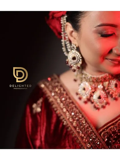 A serene bridal portrait with soft red lighting. This close-up focuses on her beautiful jewelry and the peaceful expression on her face.
