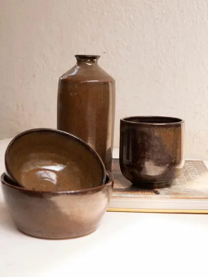 A set of bowls, a vase, and a cup all finished in our Copper Patina glaze. This demonstrates how the glaze behaves on different forms, creating a cohesive and earthy look.