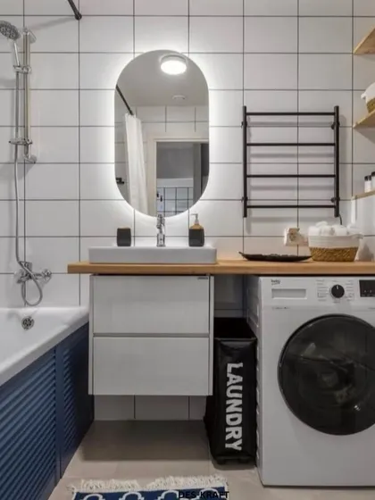 A highly functional and stylish bathroom design, featuring a space-saving layout that includes a washing machine next to the vanity. The blue and white color scheme keeps it fresh.
