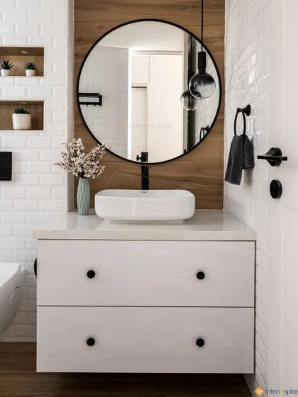 This contemporary bathroom features a beautiful mix of textures, with white subway tiles and a wood-panelled accent wall. The round mirror and floating vanity keep the design clean and elegant.