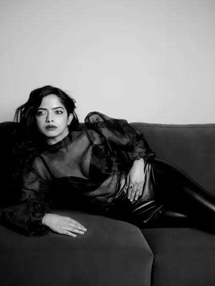 A reclining pose from the indoor B&W shoot. The composition and lighting create a classic, almost painterly quality, reminiscent of vintage film noir.