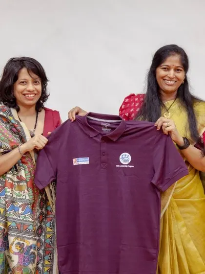 Two of our program leaders hold up a team t-shirt during the graduation ceremony. This gesture symbolizes the partnership and collaborative effort that makes the Female Athlete Leadership Programme possible.