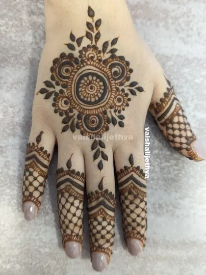 A beautiful back-hand mandala design. The central floral motif is surrounded by delicate leafy patterns, and the fingers have a net-like design.