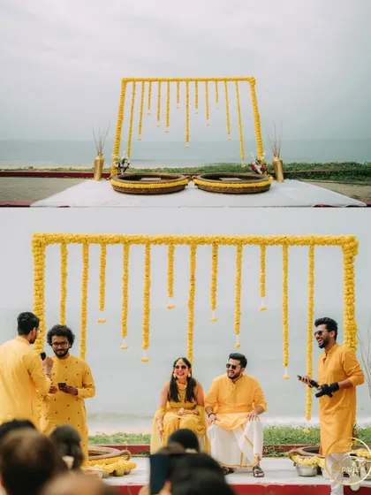 A minimalist Haldi setup on the beach, with a simple frame adorned with hanging marigold strings against the sea.