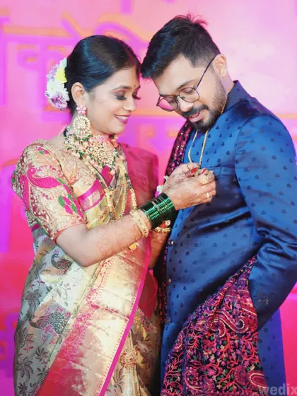 A candid moment from an engagement party where the bride playfully adjusts something on the groom's jacket.
