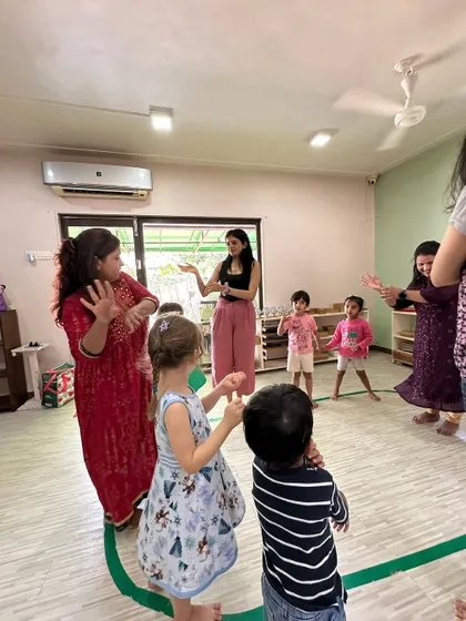 A teacher guides the children through a hand-gesture song, a technique we use to improve motor skills and rhythmic coordination.
