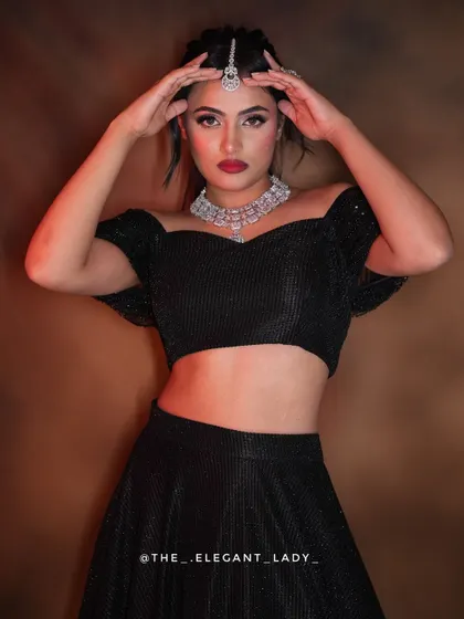 A bold and confident pose showing the full effect of the off-shoulder black lehenga with the brilliant CZ necklace and maang tikka.