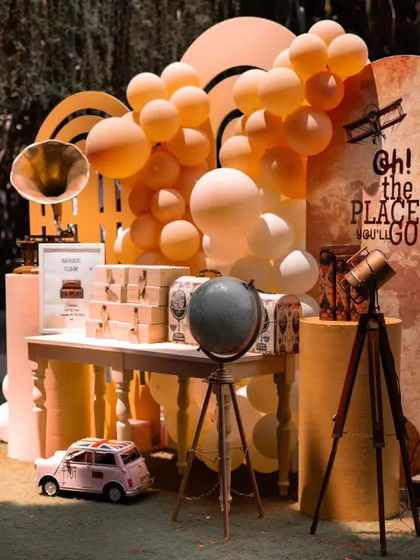 An adventurous "Oh, the Places You'll Go!" travel theme for a baby shower. The decor is filled with vintage-inspired travel elements like a globe, a telescope, a gramophone, and old-fashioned suitcases.