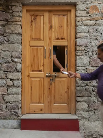 The new wooden entrance door, complete with a ticket window, blends modern function with traditional design, set within the building's original stone masonry.