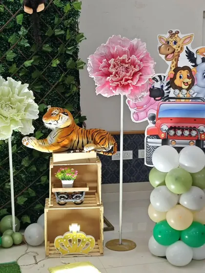 A close-up of the charming details from a jungle party. A plush tiger rests on wooden crates next to a cutout of safari animals in a jeep, showing the mix of textures and props I use to create a rich, layered look.