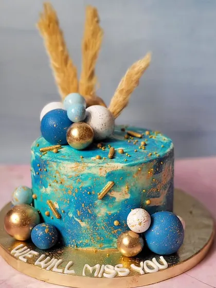 Beauty in blue. This cake features a blue and gold marbled buttercream effect, decorated with chocolate spheres and dried pampas grass for a modern, boho vibe.