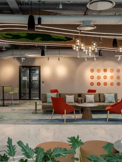 A collaborative lounge area with varied seating options and moss wall art. The quote on the wall, "<Systems that never fail for a world that never sleeps>", reinforces the client's brand identity within a relaxed, creative setting.
