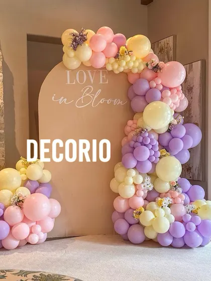 A beautiful 'Love in Bloom' themed setup with a pastel balloon garland in shades of pink, purple, and yellow. The soft colors and floral accents create a romantic and whimsical ambiance.