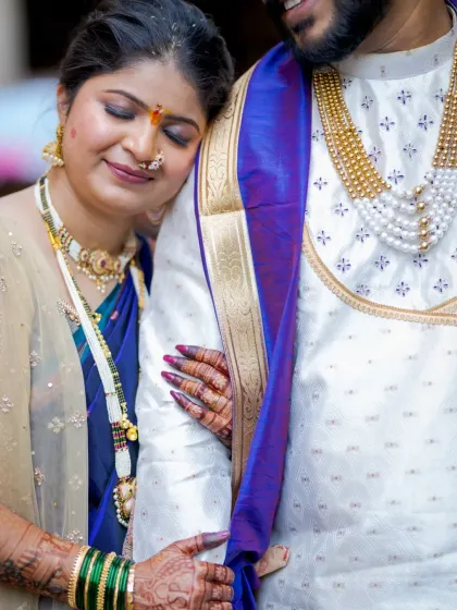A close-up shot focusing on the bride resting her head on the groom's shoulder, highlighting her intricate 'nath' and henna.