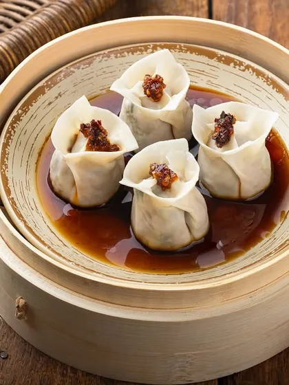 Steamed chicken dim sum presented in a traditional bamboo steamer. The lighting is carefully controlled to highlight the delicate texture of the wrapper and the savory filling, demonstrating a clean approach to Pan-Asian food photography.