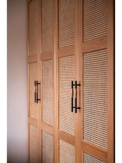 A detail shot of the custom wardrobe handles, which combine dark metal with a touch of rattan, showcasing our attention to even the smallest elements.